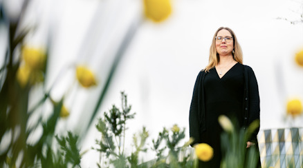 Anna Dahlgren står i gräset bland gula blommor.