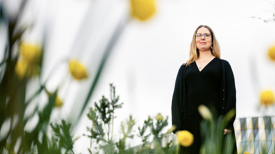 Anna Dahlgren står i gräset bland gula blommor.