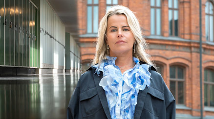 En bild av Anna Olskog mot bakgrund av en skolkorridor