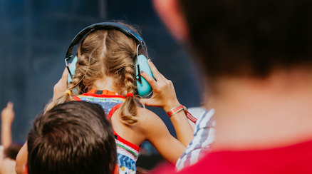 Ett barn som bär hörselkåpor i klassrummet, sett bakifrån