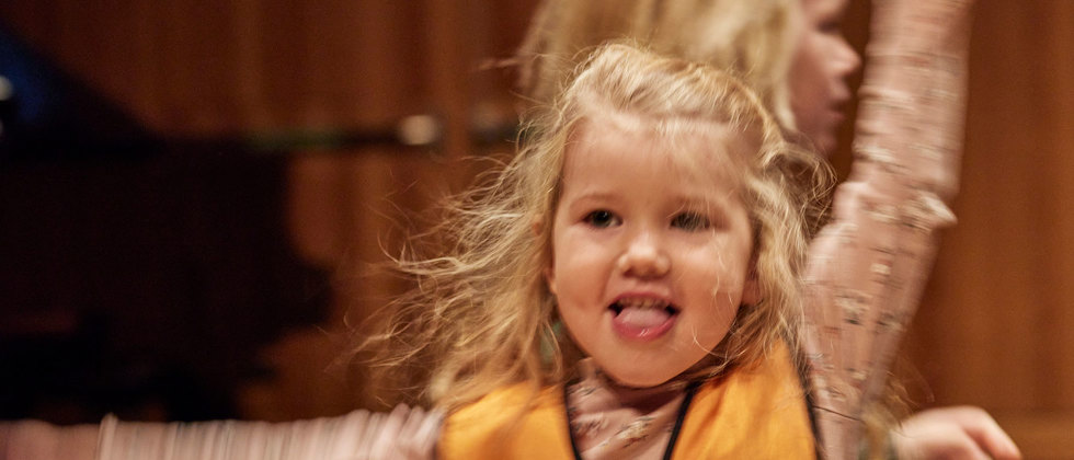 Ett litet barn dansar koncentrerat och ett annat barn skymtar i bakgrunden.