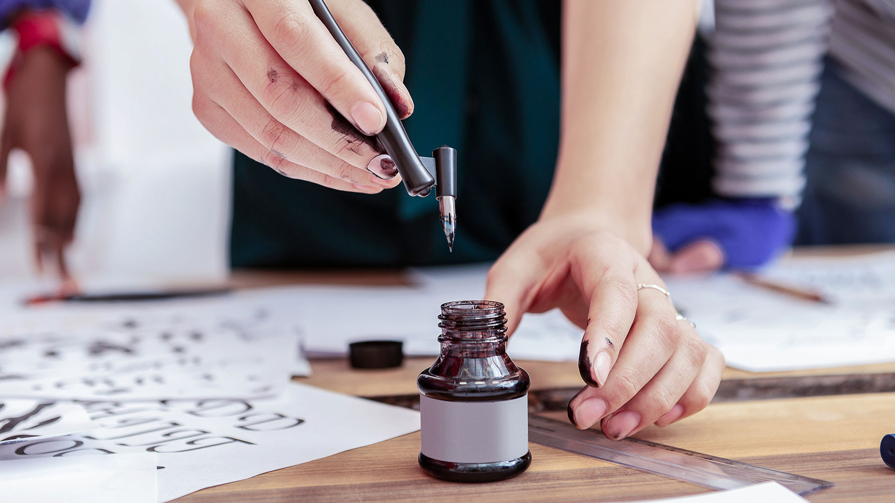 En genrebild av en person som målar svarta tecken på ett papper som ligger på ett bord