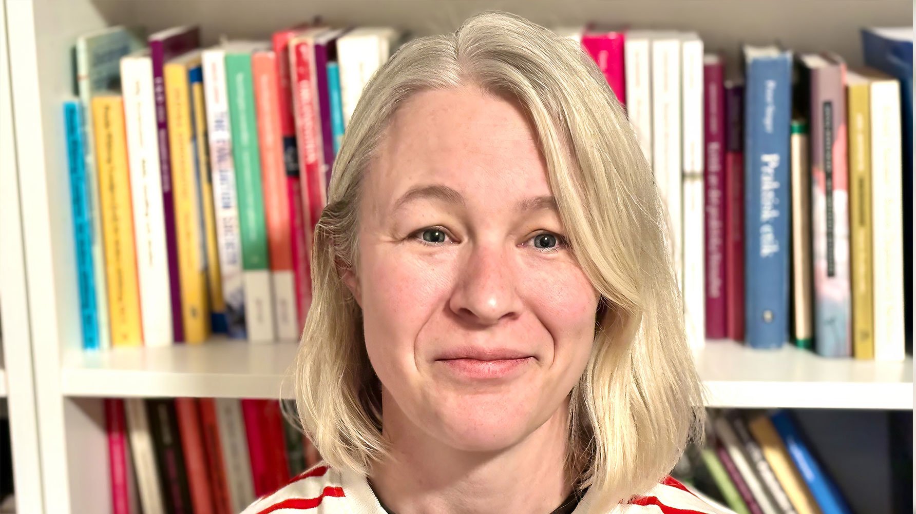 Ett portr&#xE4;tt av Elna Sivhed framf&#xF6;r en bokhylla full med b&#xF6;cker