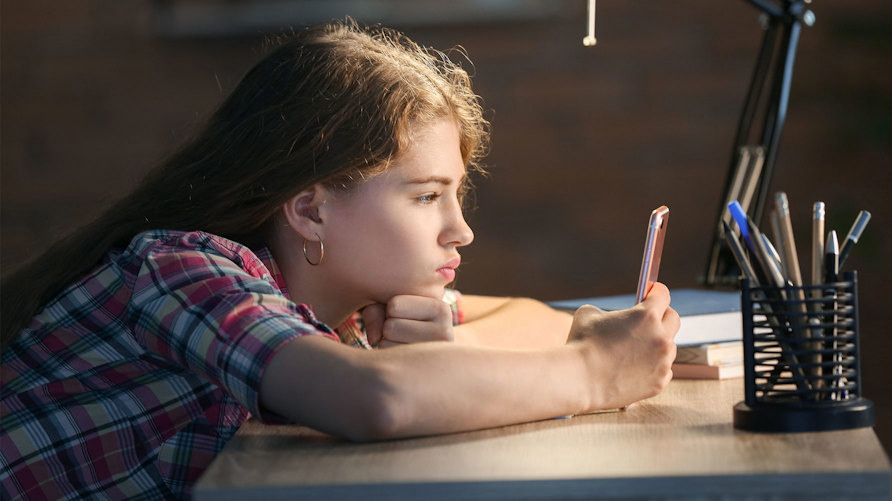 En flicka tittar på en mobiltelefon.