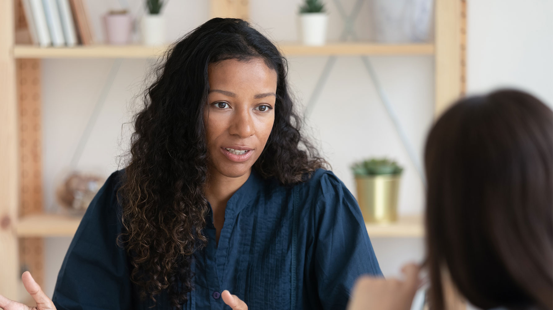 En genrebild av en lärare som förklarar något för en elev, eleven sitter i förgrunden och anas bara