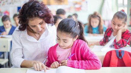 En lärare och en elev läser i en bok.