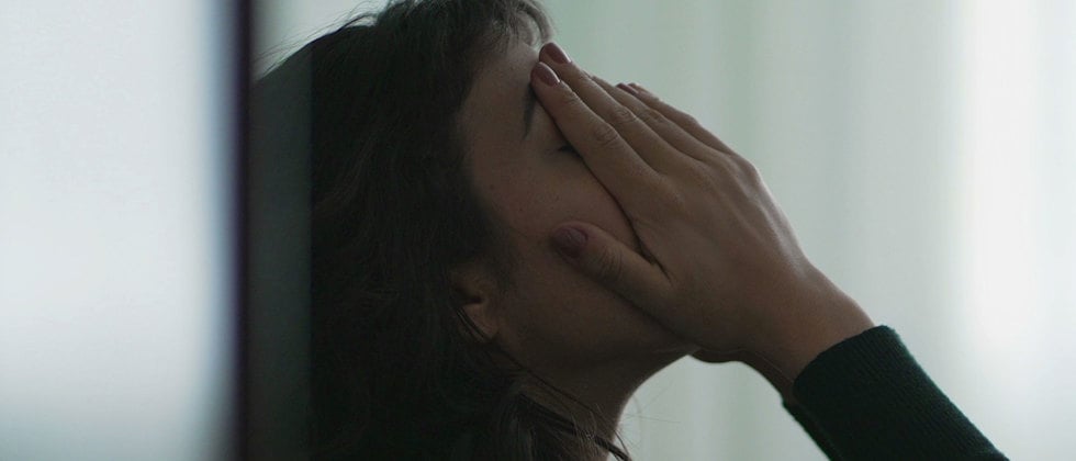 En närbild av en uppgiven person i vad som ser ut att vara en korridorsmiljö, genrebild.