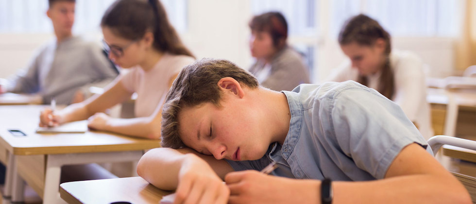 Pojke som sover på skolbänken.