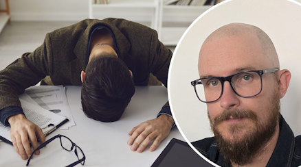 En stressad man som ligger över sitt skrivbord och läraren Mathias Edbäck Leo