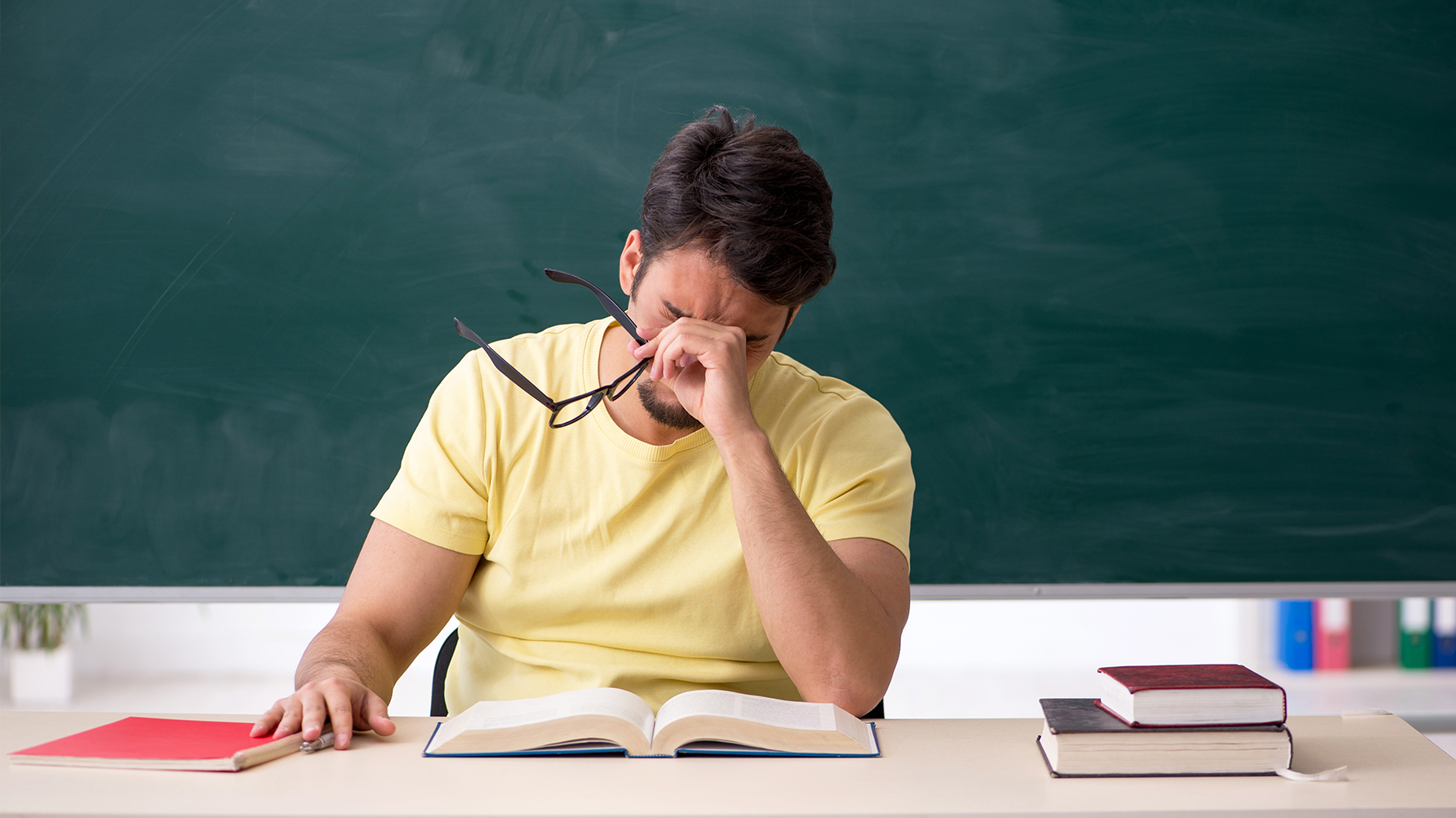 En lärare vid sin kateder som håller händerna för ansiktet