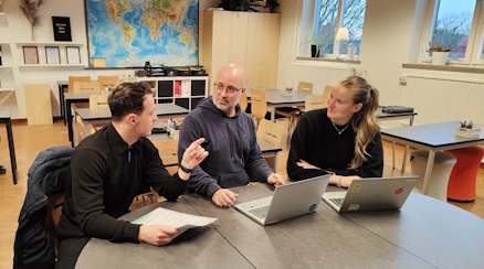 Mergim Mehmeti, Lucas Lennartsson och Amanda Bjerstam samtalar i ett klassrum, med varsin laptop framför sig