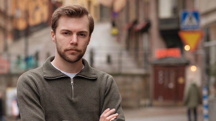Ett porträtt av Adam Kedert med allvarlig min och armarna i kors
